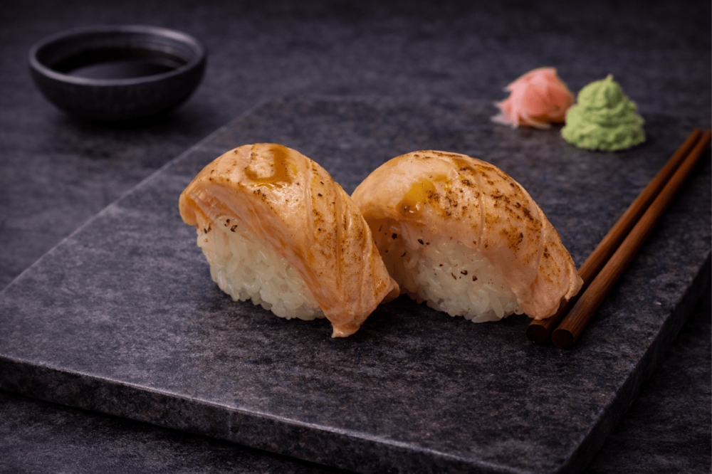 Sushi med flambert laks
Oppdag smaken av saftig, lett flambert laks – toppet med rik unagi-saus som gir en perfekt balanse mellom sødme og umami. En favoritt blant mange og et must for deg som elsker mild og smakfull sushi.